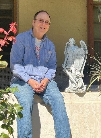 Br. Chris poses with the statue of St. Michael in the garden