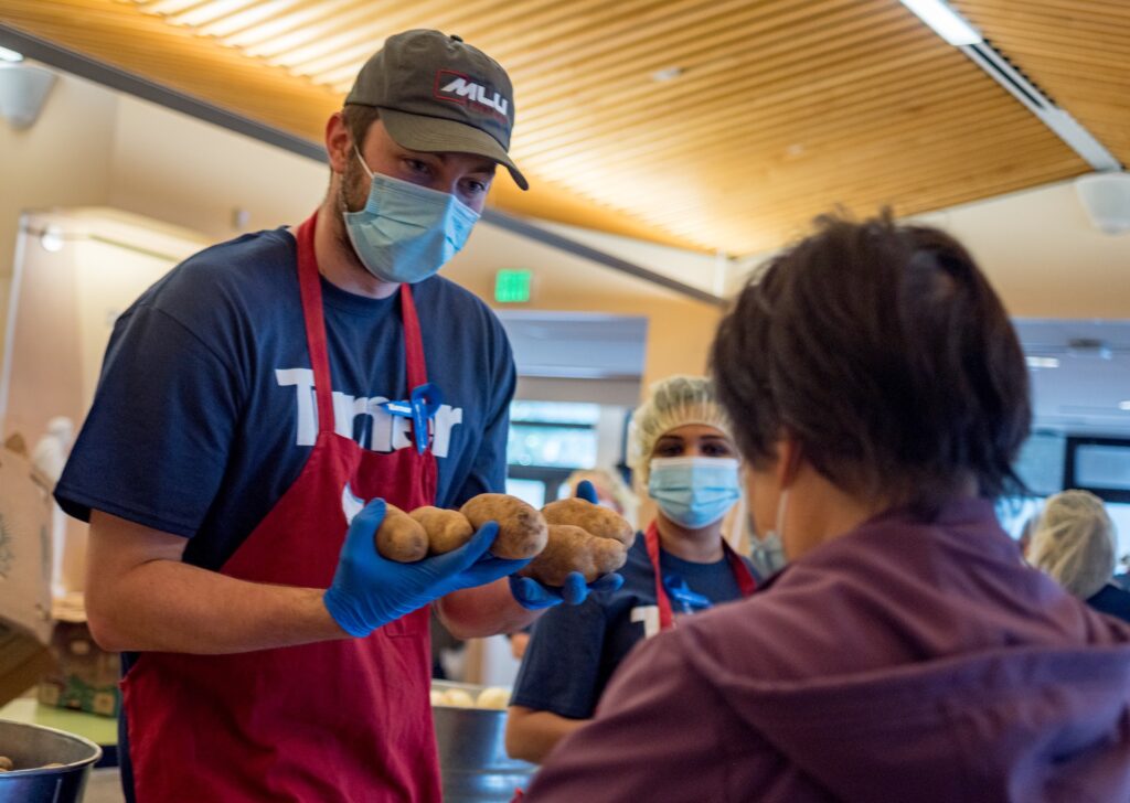 A turner Construction Employee distributes potatoes to a senior at the St. Anthony's farmers market